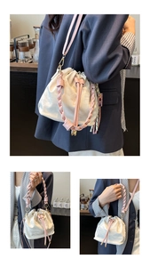 Close-up of white bucket bag with pink woven handle and detachable shoulder strap