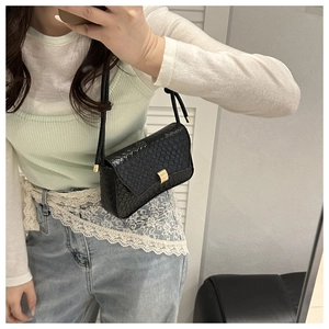Detail of black faux leather shoulder bag with snake skin texture and gold clasp