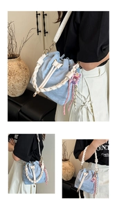 Detail of light blue nylon bucket bag featuring white woven handle and cartoon charm