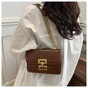 Brown glossy quilted crossbody bag with gold geometric clasp shown on a model