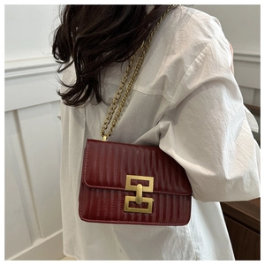 Detail of burgundy quilted shoulder bag with gold chain and square metal clasp on model