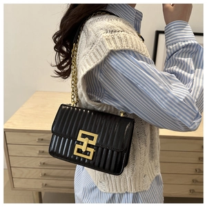 Vertical quilted black leather shoulder bag with gold interlocking lock on a female model