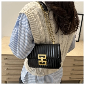 Close-up of black quilted flap bag with gold chain strap and geometric metal buckle
