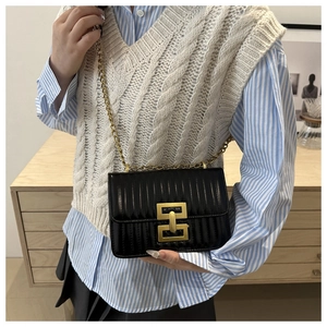 Detail shot of black quilted faux leather crossbody bag with golden geometric metal clasp