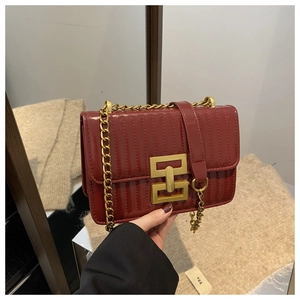Detailed close-up of dark red patent leather bag with vertical stitching and gold metal buckle