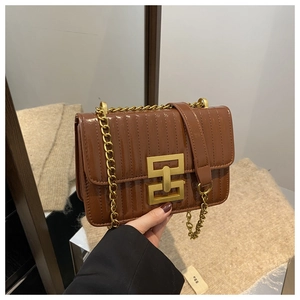 Detail of brown quilted patent leather shoulder bag with golden geometric lock and chain strap