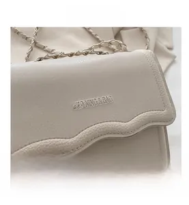 Close-up of cream square bag with wavy flap design and lychee texture detail