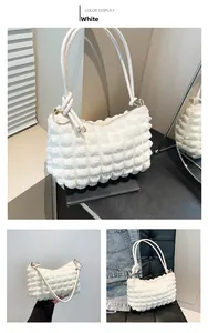 Close-up of white bubbly textured shoulder bag with chic knot details and gold zipper