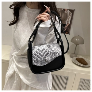 Detalle de bolso negro de hombro con bordado tradicional de ondas y motivos chinos