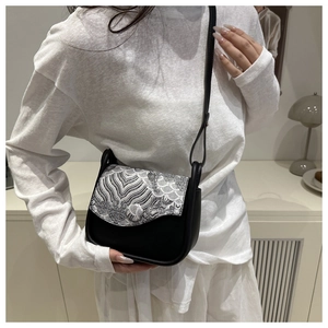 Detail of a Chinese style crossbody bag with black embroidery and artistic texture flap
