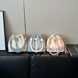 Minimalist drawstring bucket bags in light blue, off-white, and pink with woven handles