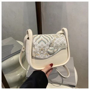 Detail of cream crossbody bag featuring elegant Chinese mountain and cloud embroidery