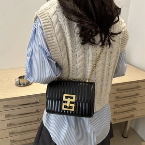 Quilted black shoulder bag with gold chain strap shown on model in a stylish setting