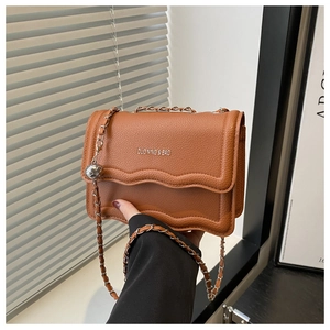 Detail of brown litchi pattern square bag with wavy flap and metal ball chain strap