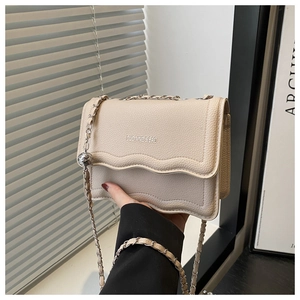 Detail of lychee textured beige leather shoulder bag with wavy edge and silver chain strap