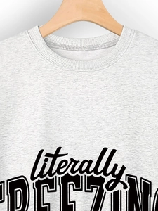 Detail of grey crewneck sweatshirt featuring literally FREEZING artistic black text print