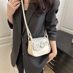 Chic cream crossbody bag with vintage embroidery detail shown on a model's shoulder