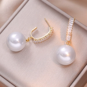 Elegant gold pearl drop earrings with sparkling cubic zirconia on luxury silk background