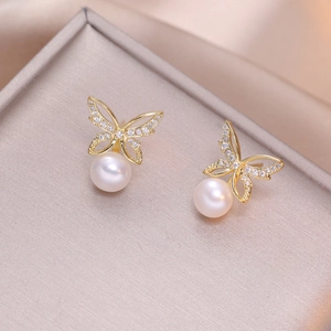 Elegant gold butterfly earrings with sparkling crystals and white pearls on velvet tray
