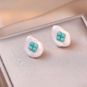Baroque pearl drop earrings with turquoise inlay and golden rope frame on textured surface