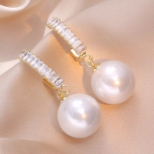 Elegant gold earrings with large white round pearls and sparkling rectangular crystals