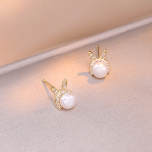 Elegant gold rabbit pearl earrings with sparkling zircon inlay on warm silk background