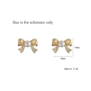 Elegant gold bow earrings with crystal pave and freshwater pearl center on white backdrop