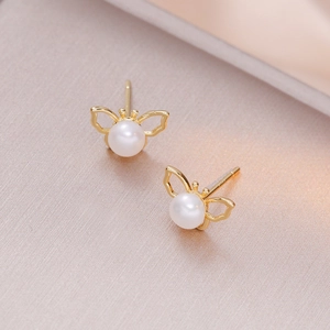 Élégantes boucles d'oreilles papillon dorées avec perles d'eau douce naturelles sur fond champagne