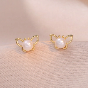 Boucles d'oreilles papillon dorées avec perles d'eau douce sur tissu en satin rose