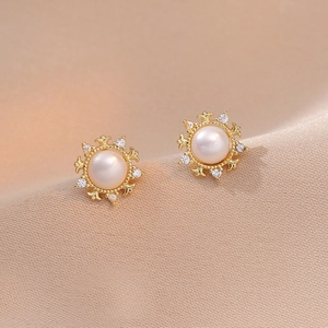 Elegant floral pearl stud earrings with gold metal petals and crystal accents on silk