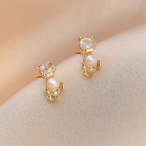 Elegant gold cat-shaped earrings with freshwater pearls and sparkling zircons on silk