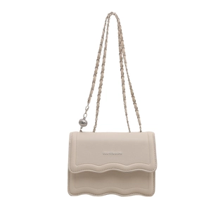 Cream shoulder bag with wave edge flap and metal chain strap on white background