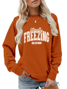 Detail of white artistic lettering printed on a burnt orange oversized crewneck sweatshirt