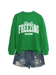 Detailed flat lay of a green crewneck sweatshirt with freezing print and ripped denim shorts