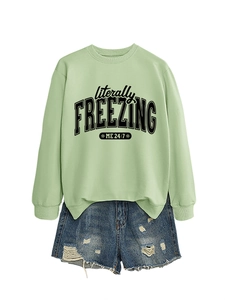 Flat lay of a mint green sweatshirt with 'literally freezing' text and ripped denim shorts