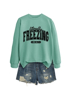 Detail of mint green sweatshirt with 'literally freezing' print and ripped denim shorts