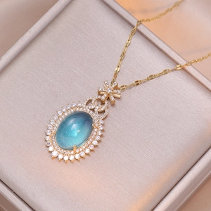 Collier doré élégant avec pendentif ovale en zircon émeraude dans un écrin à bijoux