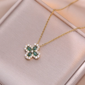 Elegante collana dorata con pendente a quadrifoglio verde smeraldo su portagioie rosa