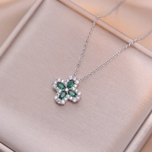 Elegante collana con quadrifoglio e zirconi verdi posata su una confezione regalo dorata