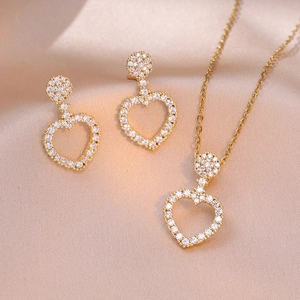 Elegante gouden hartvormige sieradenset met ketting en oorbellen op champagne zijde