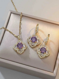 Dettaglio set gioielli dorati con ciondolo a quadrifoglio in zircone viola e orecchini
