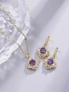 Dettaglio di set collana e orecchini a forma di fiore dorato con zirconi viola