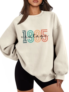 Close-up of 1985 vintage print on oversized cream sweatshirt with soft fabric texture