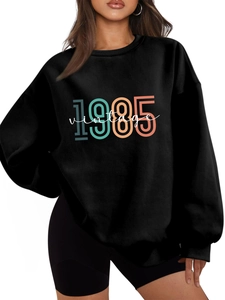 Close-up of classic black sweatshirt with 1985 vintage print and ribbed neckline