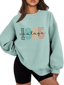 Detail of mint green oversized pullover with 1985 vintage graphic and dropped shoulders