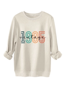 Close-up of 1985 vintage print on beige crewneck sweatshirt showing fabric texture