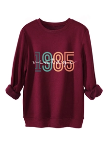 Macro detail of the thick fleece lining and vintage 1985 graphic on this red sweatshirt