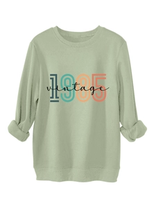 Detail of sage green 1985 vintage sweatshirt showing ribbed hem and printed graphic