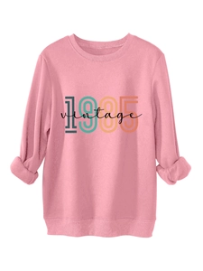 Close-up of pink long-sleeve sweatshirt featuring 1985 vintage print and ribbed cuffs