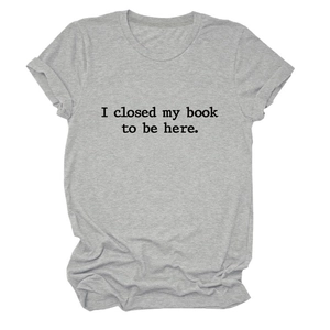Détail d'un t-shirt gris à col rond avec le slogan 'I closed my book to be here'